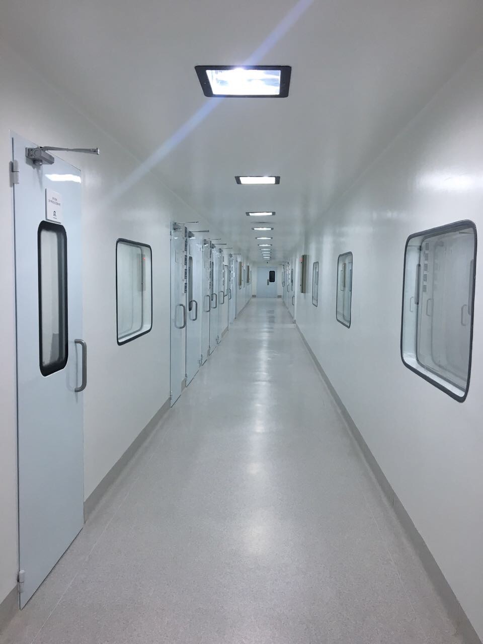 Corredor de salas limpias con puertas y visores sanitarios