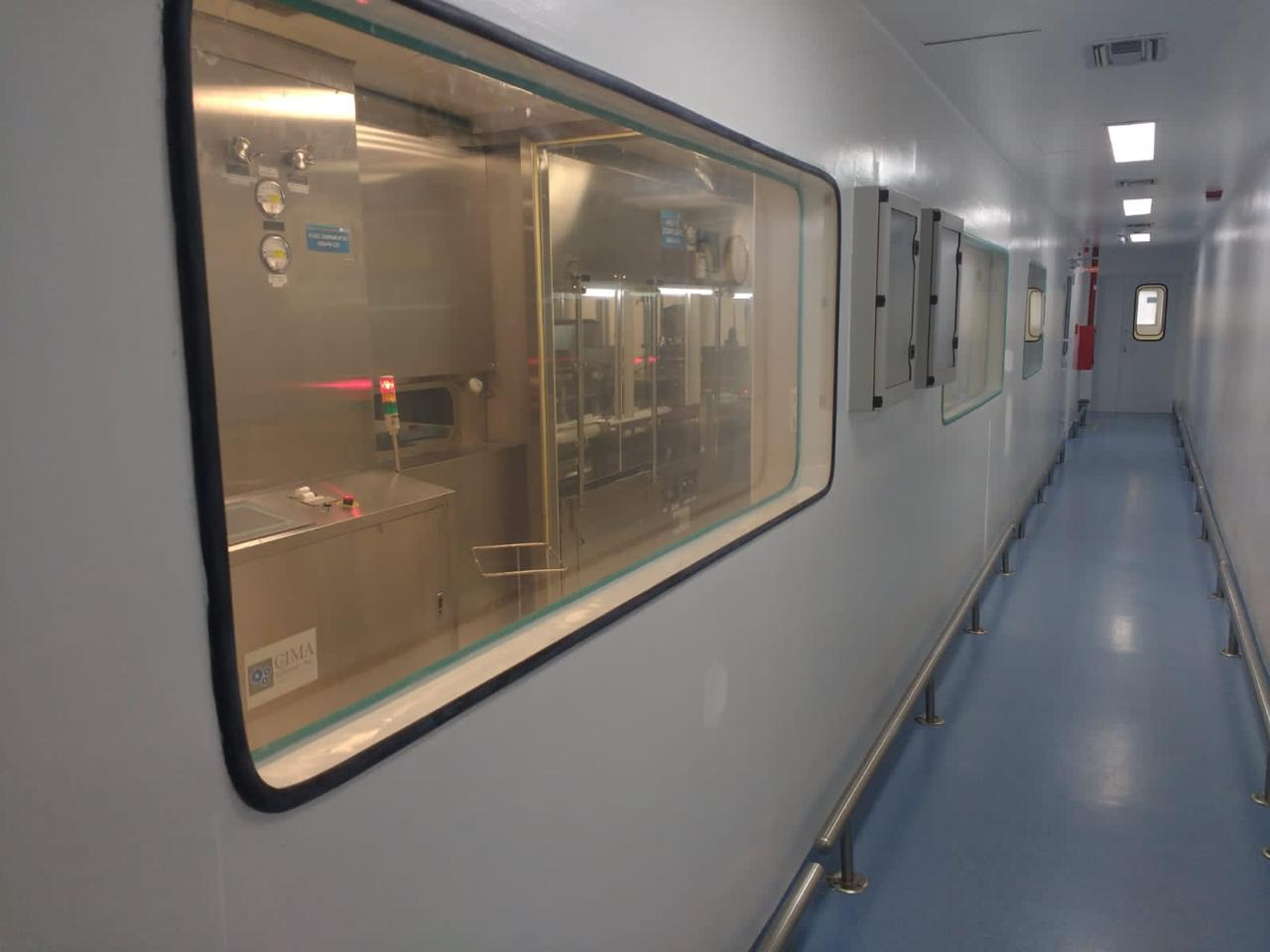 Corredor limpio terminado con visor hacia equipamiento de proceso