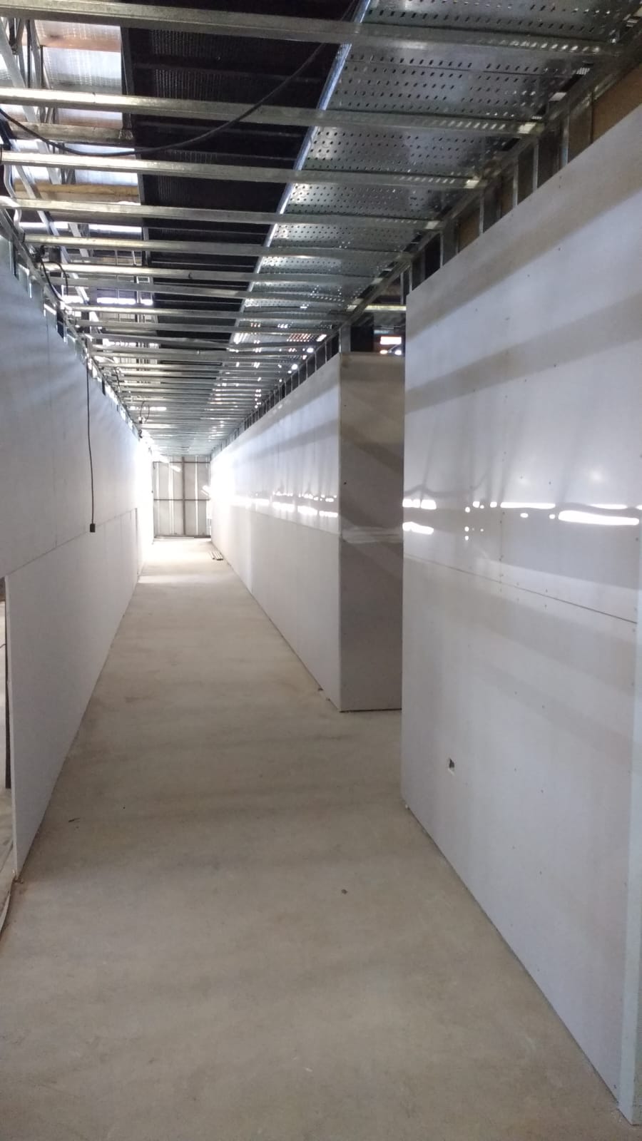 Corredor durante la obra con estructura metálica e instalaciones superiores